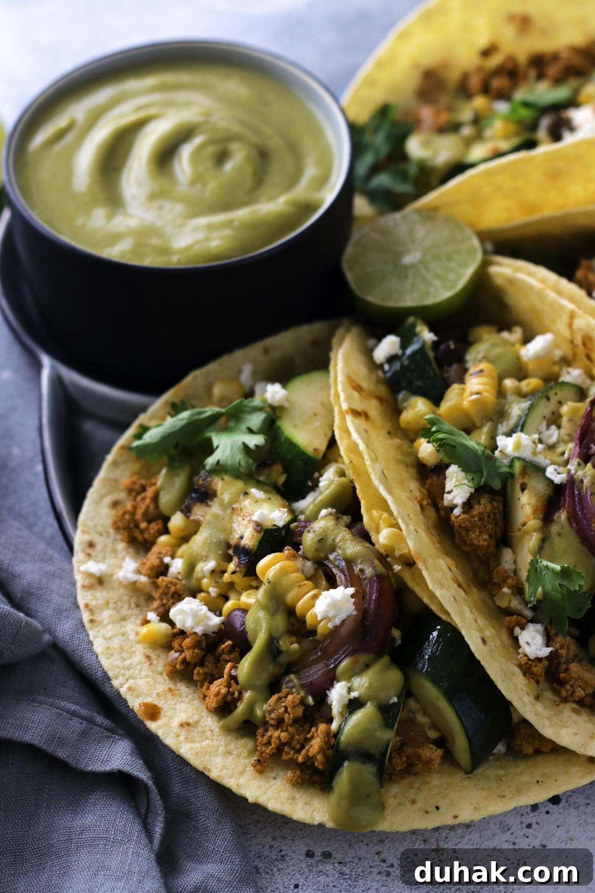 Creamy Avocado Vegan Dressing Recipe for Salads & Bowls 4 Closeup on the delicious Corn Zucchini Tacos with Avocado Sauce on the side and a piece of lime in between