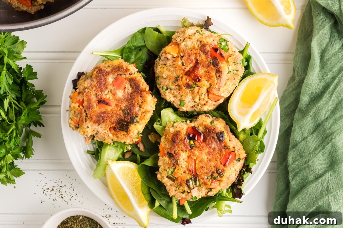 Top down view of three golden brown crispy fried tuna patties sitting on a bed of lettuce. Hostess At Heart