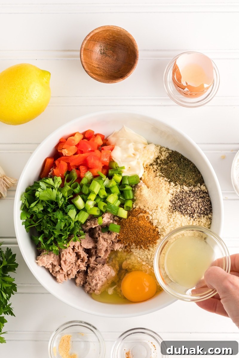 Ingredients used to make tuna patties recipe including canned tuna, egg, old bay seasoning, salt, garlic powder, lemon juice, mayo, bell pepper, and green onion - Hostess At Heart