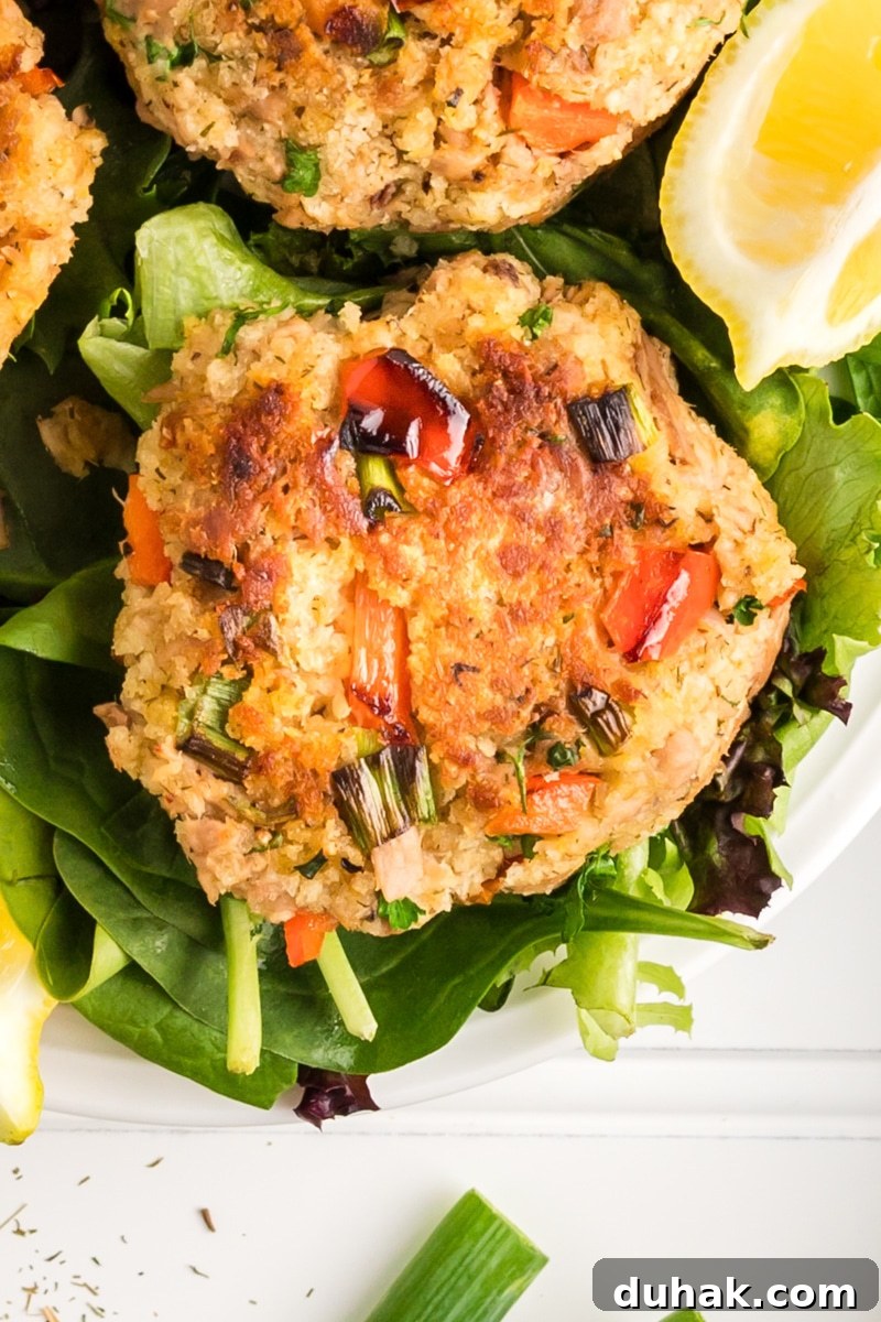 Close-up view of a golden brown crispy tuna fish pattie sitting on a bed of lettuce. Hostess At Heart