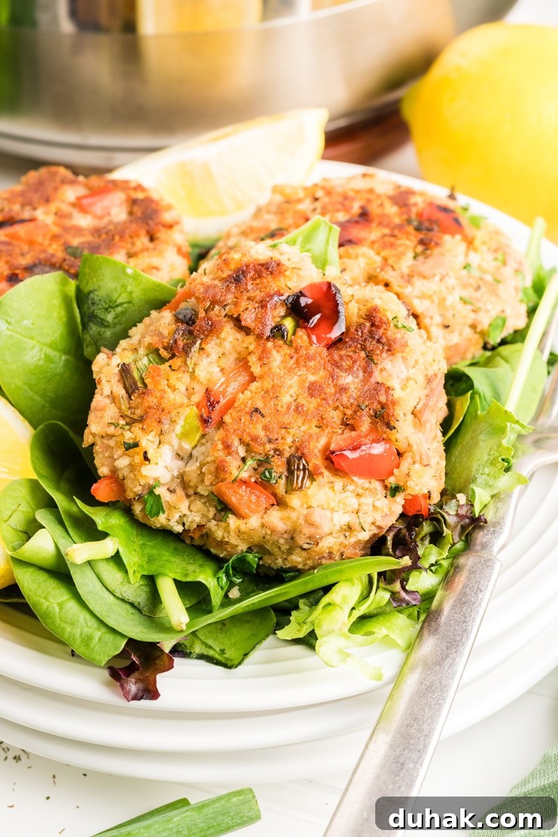 Front view of a tuna cake fried golden brown sitting on a bed of lettuce - Hostess At Heart