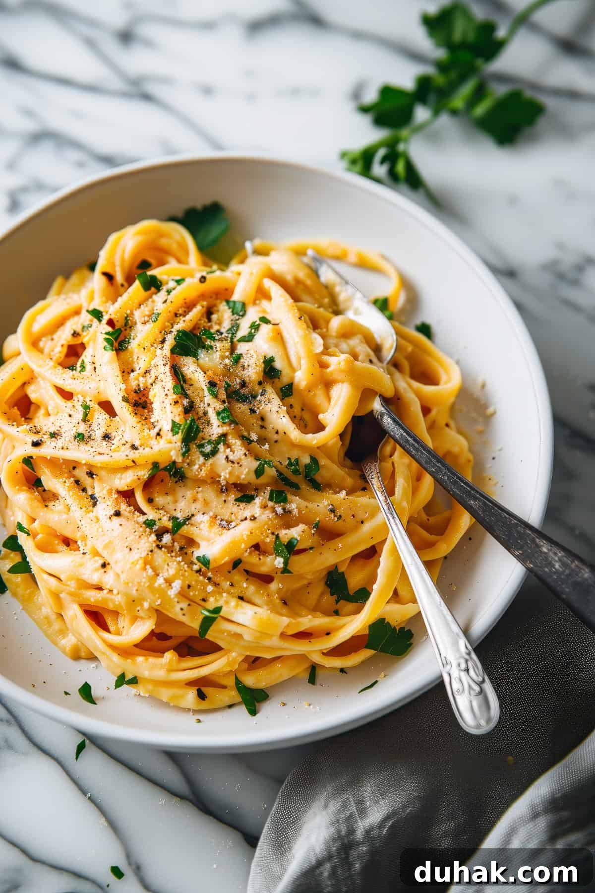 Roasted cauliflower & pumpkin fettuccine Alfredo: a cosy pasta night in with creamy roasted cauliflower sauce, sweet roasted pumpkin, mushrooms and figs. Creamy pumpkin alfredo with parmesan cheese in a white bowl.