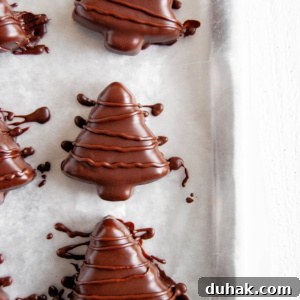 Chocolate-Covered Peanut Butter Christmas Tree Treats 7 Chocolate covered peanut butter trees on parchment paper lined baking sheet.