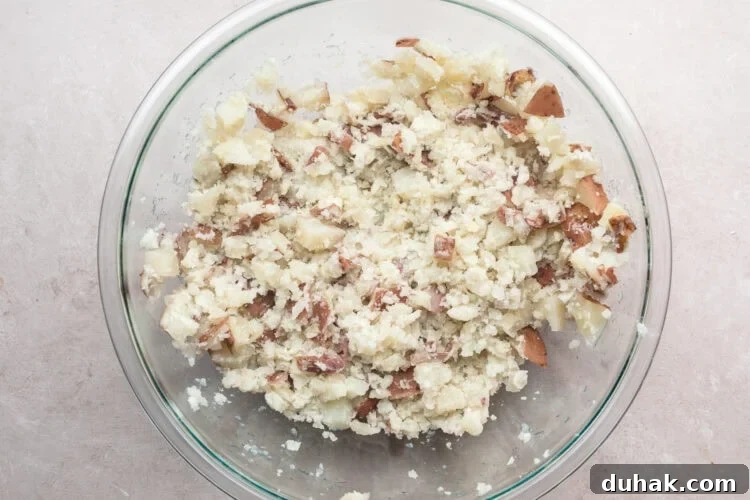 Overhead view of mashed red skin potatoes in a large glass mixing bowl.