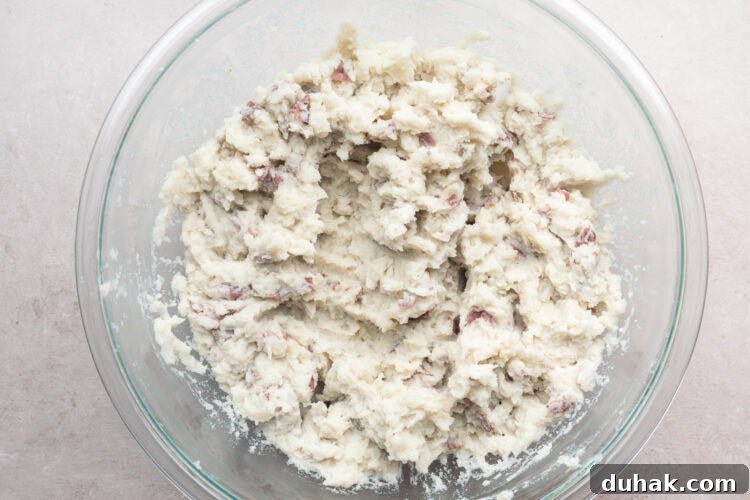Overhead view of mashed red skin potatoes in a large glass mixing bowl.