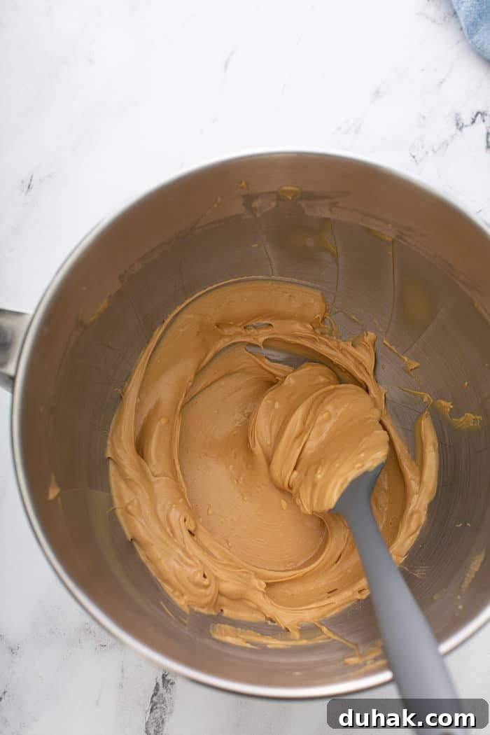 Biscoff Sandwich Cookies Recipe: Crispy Cookies with Lotus Spread Filling 4 Spatula stirring creamed biscoff spread and butter in a metal mixing bowl