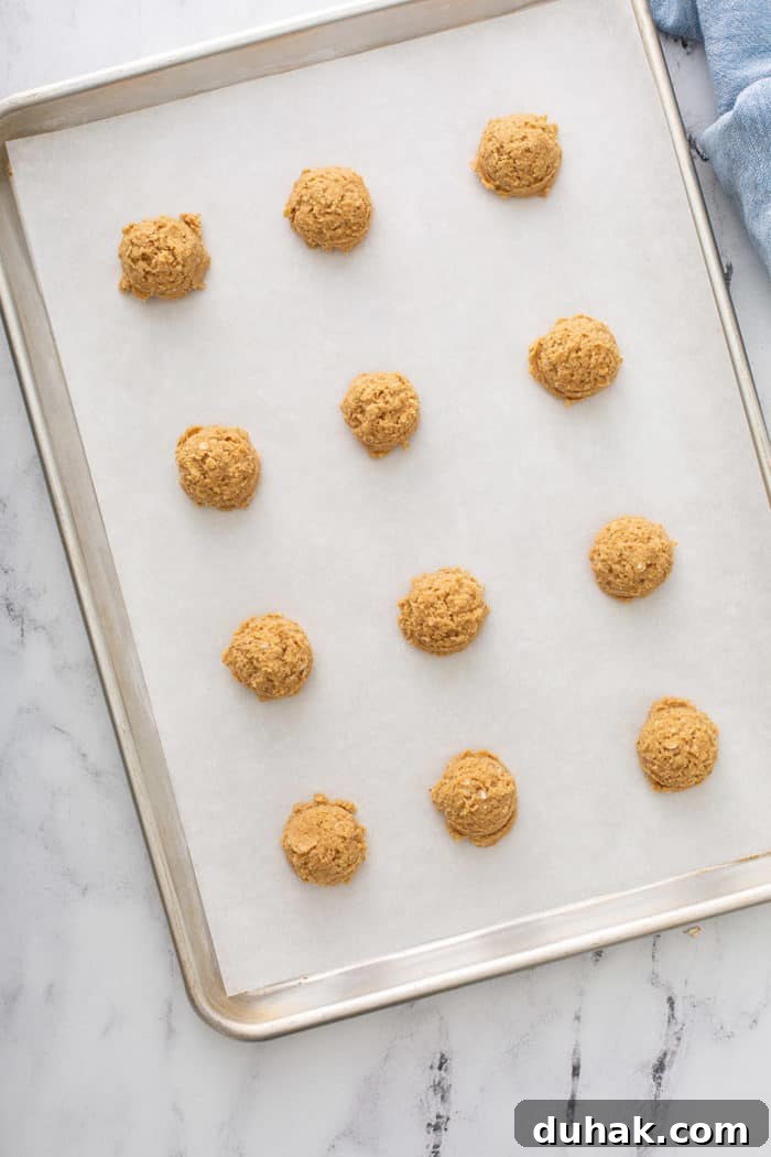 Biscoff Sandwich Cookies Recipe: Crispy Cookies with Lotus Spread Filling 6 Portioned biscoff cookie dough lined up on a parchment-lined baking sheet