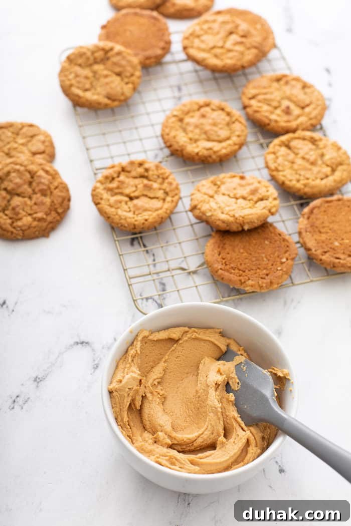 Biscoff Sandwich Cookies Recipe: Crispy Cookies with Lotus Spread Filling 8 Bowl of biscoff filling in the foreground with a wire cooling rack of biscoff cookies in the background
