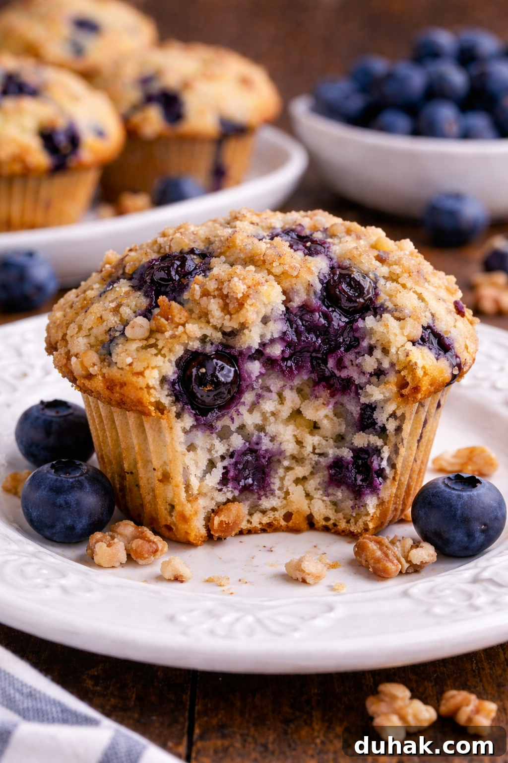 Fluffy Blueberry Muffins with Crunchy Walnuts 5 Blueberry Walnut Muffin on a pretty white plate with a bite missing