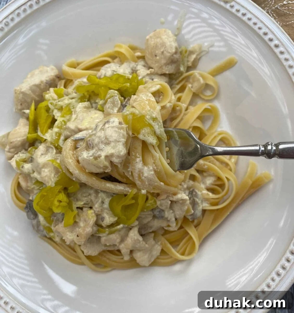 Creamy Spicy Alfredo Sauce Recipe for Pasta and Wings 2 A serving of spicy chicken Alfredo on a plate with a fork that has a scoop of pasta and sauce.