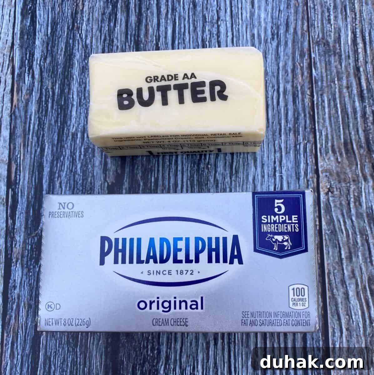 Creamy Spicy Alfredo Sauce Recipe for Pasta and Wings 4 A stick of butter and a package of cream cheese on a wood block.