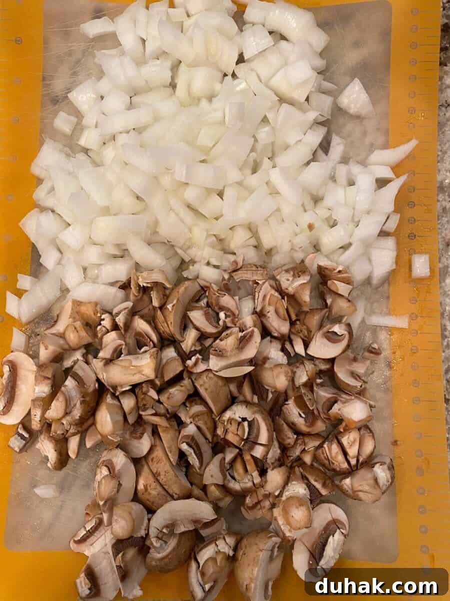 Creamy Spicy Alfredo Sauce Recipe for Pasta and Wings 5 Diced mushrooms and onions on a cutting mat.