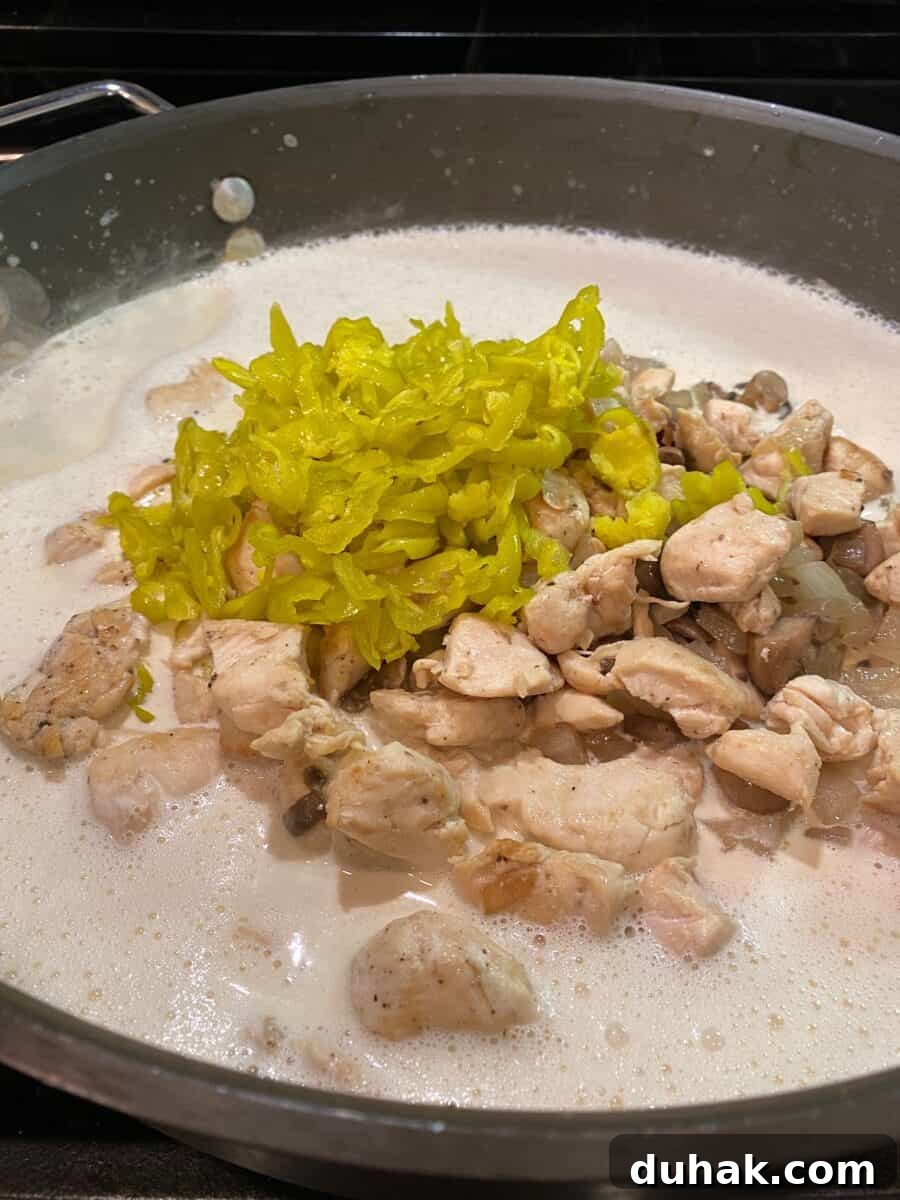 Creamy Spicy Alfredo Sauce Recipe for Pasta and Wings 9 Alfredo sauce, chicken, mushrooms, onions and pepperoncinis in a skillet.