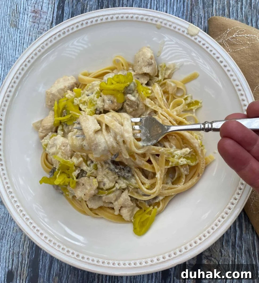 Creamy Spicy Alfredo Sauce Recipe for Pasta and Wings 10 A serving of spicy chicken Alfredo on a plate with a fork and a napkin on the side.