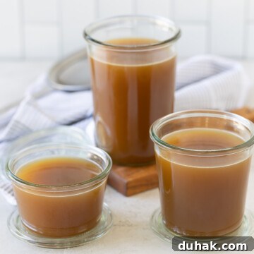 Rich brown roasted turkey broth in glass jars on a kitchen counter.