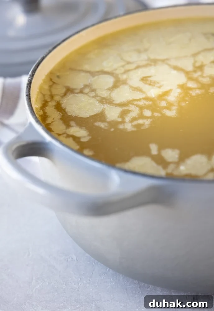 A pot of chicken broth with chilled fat layer on top, ready for defatting. 