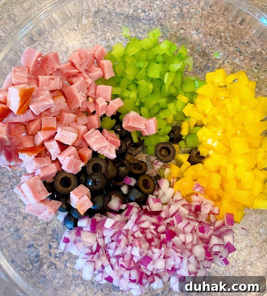 Chopped pasta salad ingredients, ham, red onion, olives, yellow pepper, celery.