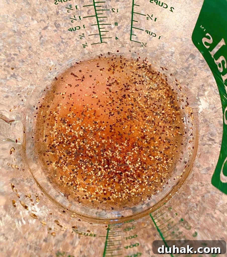 Red wine vinegar, salt, pepper, and sugar for mayo dressing in measuring cup.