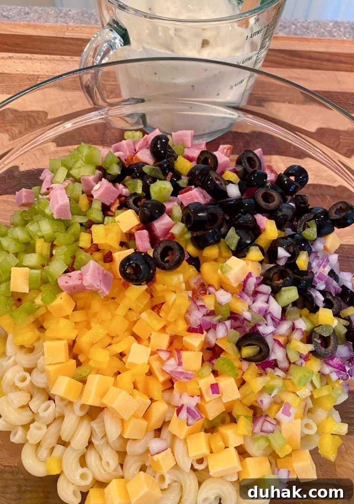Adding salad ingredients to the macaroni.
