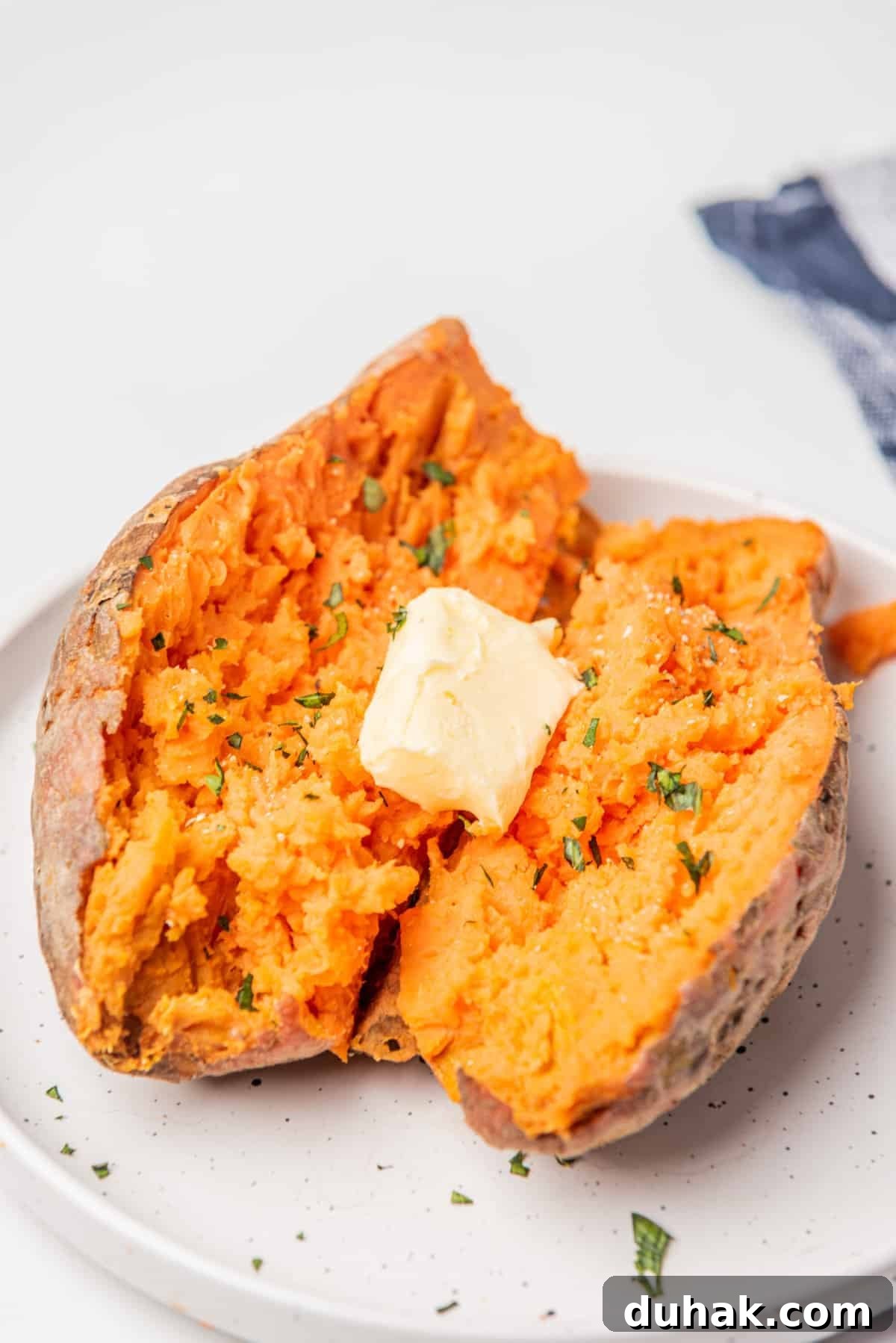 How to Cook a Sweet Potato in the Microwave Fast 7 An overhead image of microwaved sweet potatoes on a plate with a tablespoon of butter on top.