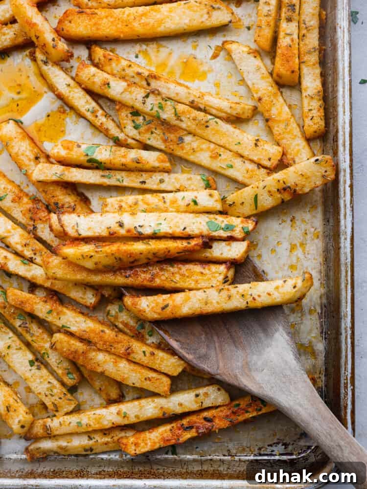 Top-down view of baked jicama fries on a baking sheet.