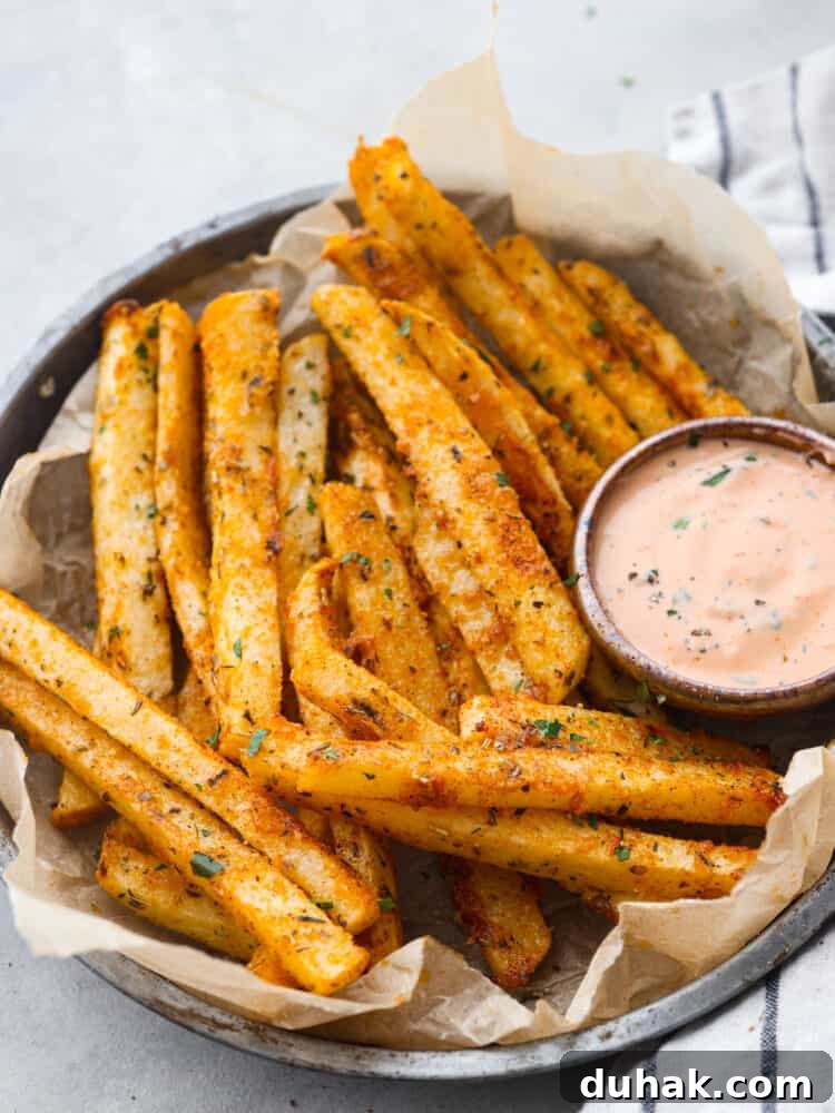 Closeup of jicama fries, served with dipping sauce in a gray bowl.