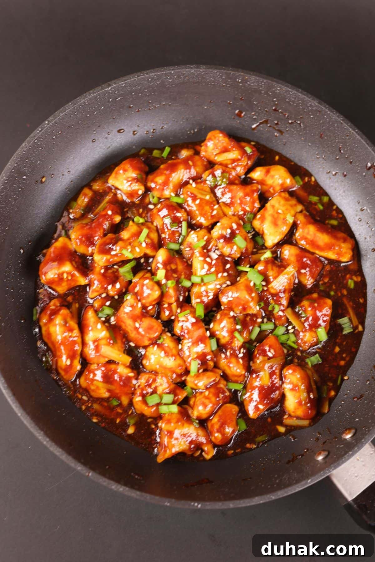 Garlic Chicken Stir-Fry with Spicy Szechuan Sauce 6 Chinese chicken in a black pan with savory garlic sauce.