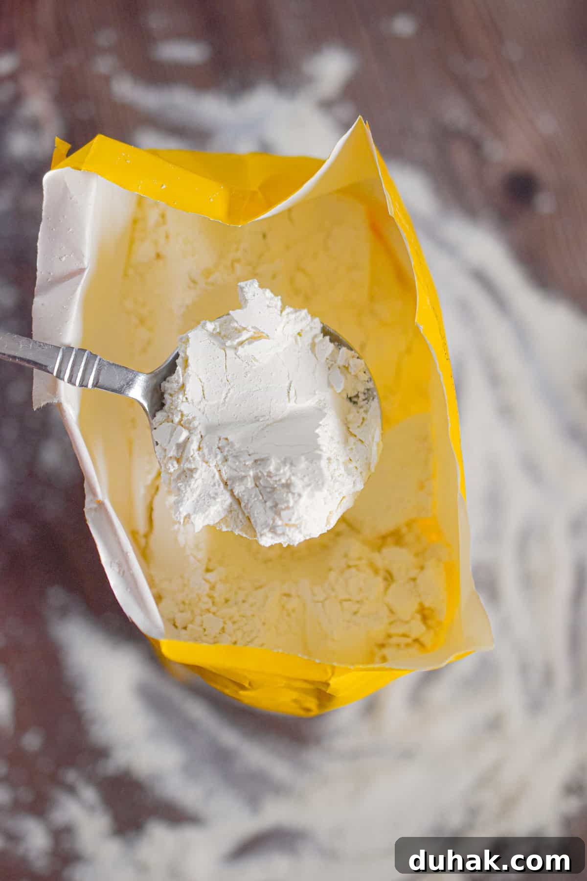 All-Purpose vs Self-Rising Flour: When to Use Each Type 4 A spoon is lifting the flour out of the bag.