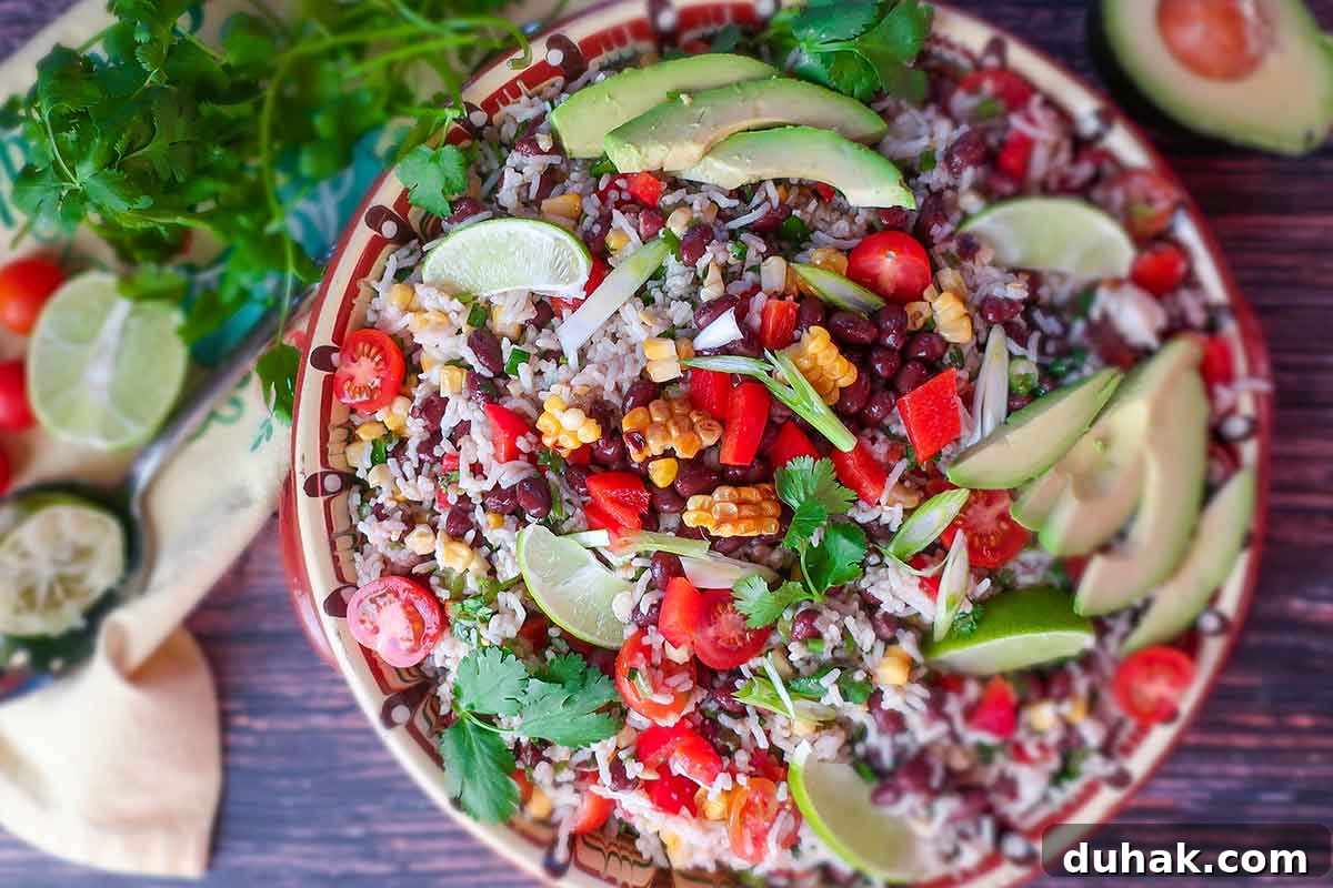 garnished black bean rice salad with avocado, lime wedges and herbs