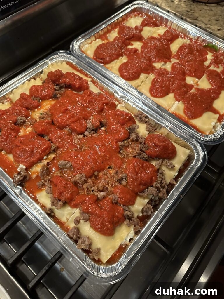 Authentic Italian Lasagna Recipe for Rich, Homemade Flavor 9 The lasagnas, one with sausage and one without, topped with tomato sauce before being put in the oven