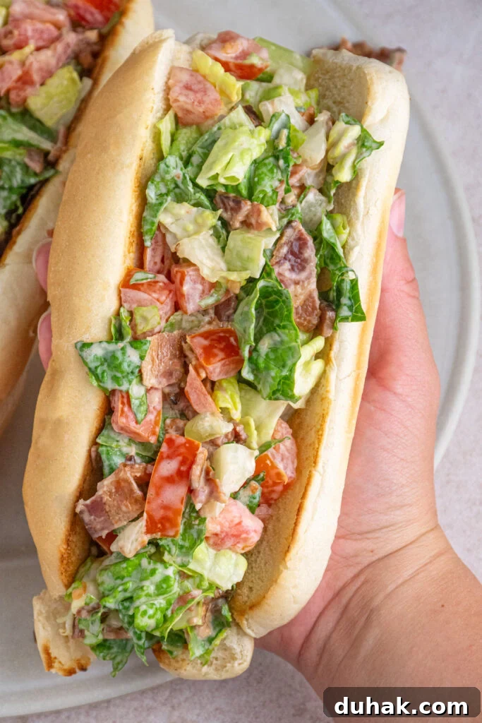 A hand holding a chopped BLT sandwich.