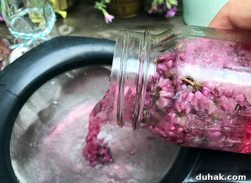 straining out chive blossoms for chive infused vinegar
