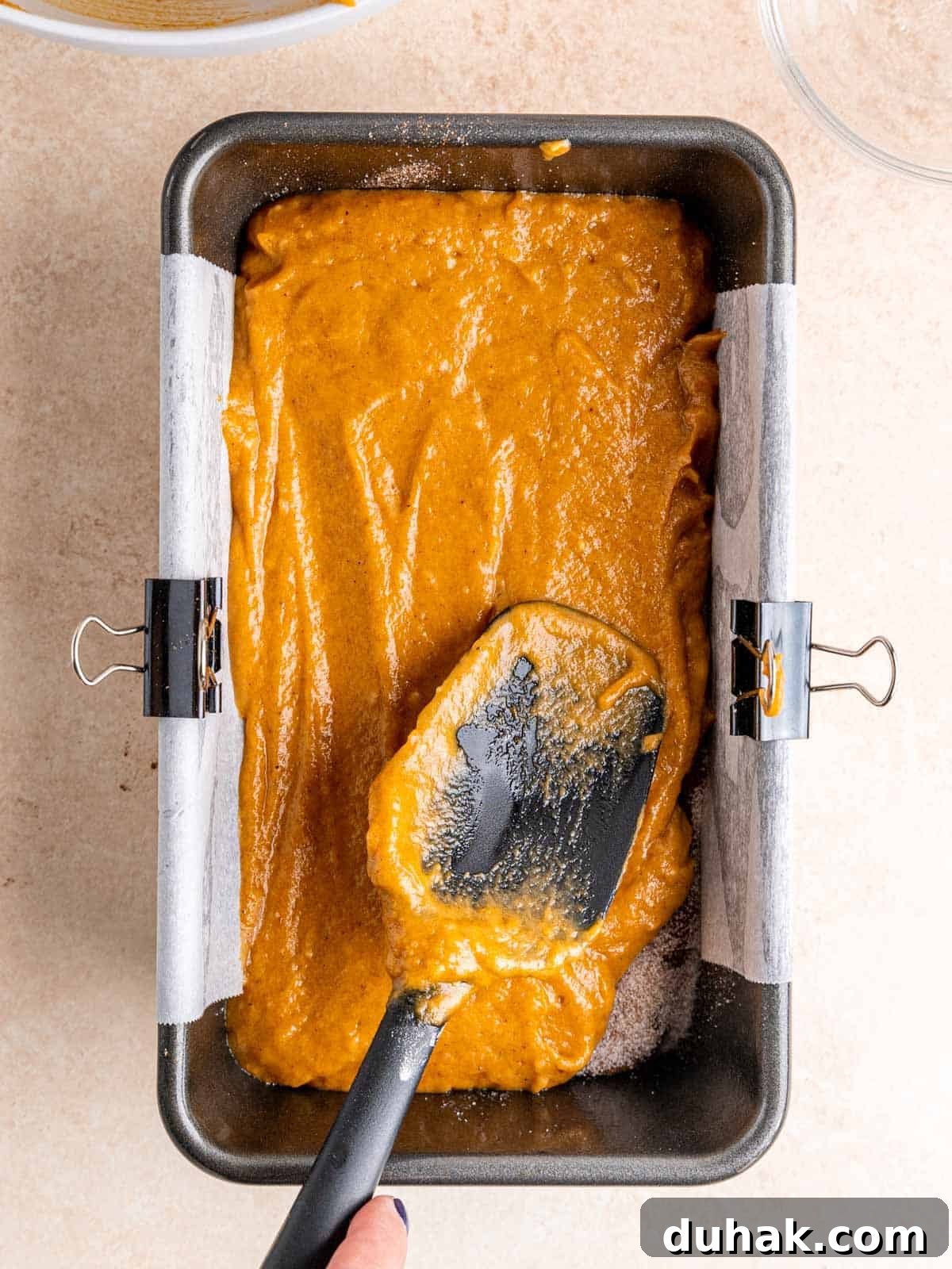 Pumpkin Snickerdoodle Quick Bread Recipe for Fall Baking 7 Spreading pumpkin bread batter into a loaf pan lined with parchment paper.