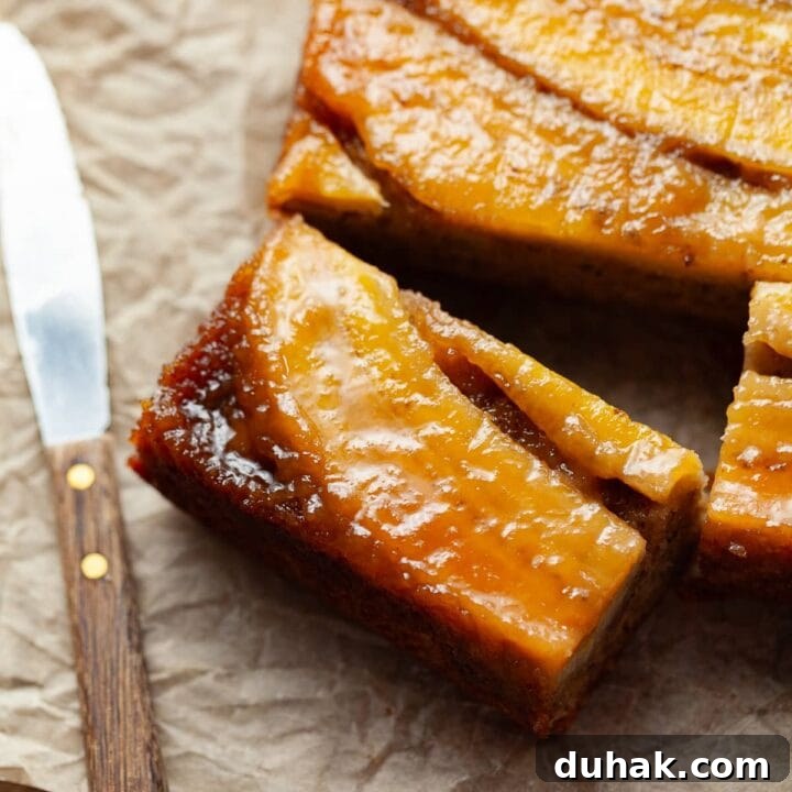 gluten free banana upside down cake. a moist banana cake topped with brown sugar caramelized bananas, on parchment paper with a small knife next to it
