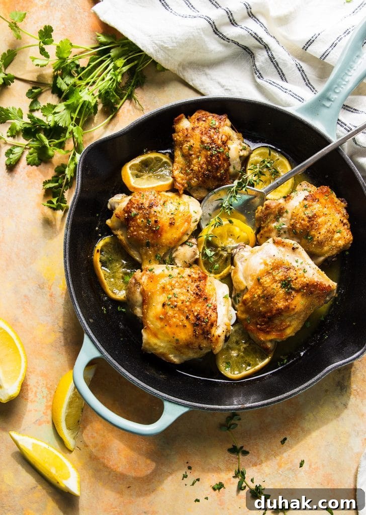 Crispy Lemon Butter Chicken Thighs with Garlic and Herbs 2 Butter chicken thighs in skillet with lemon slices and herbs