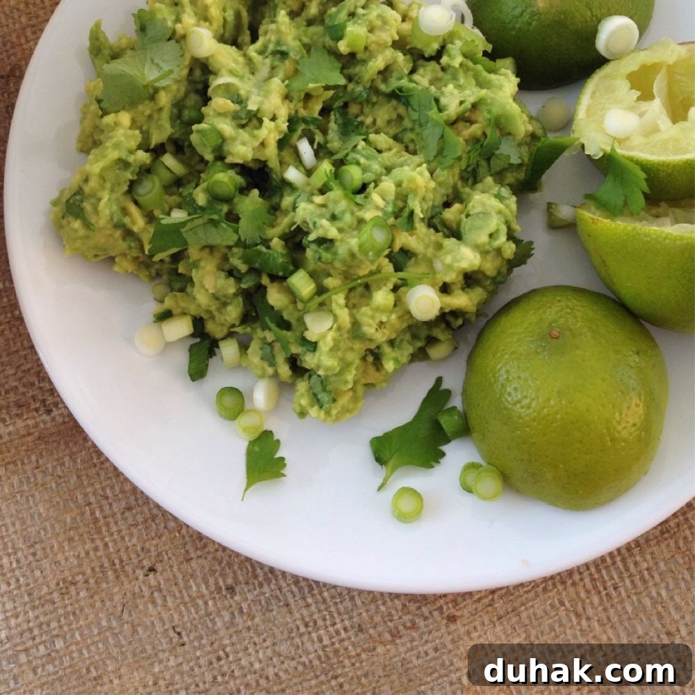 white plate with pile of homemade guacamole alongside some lime halves