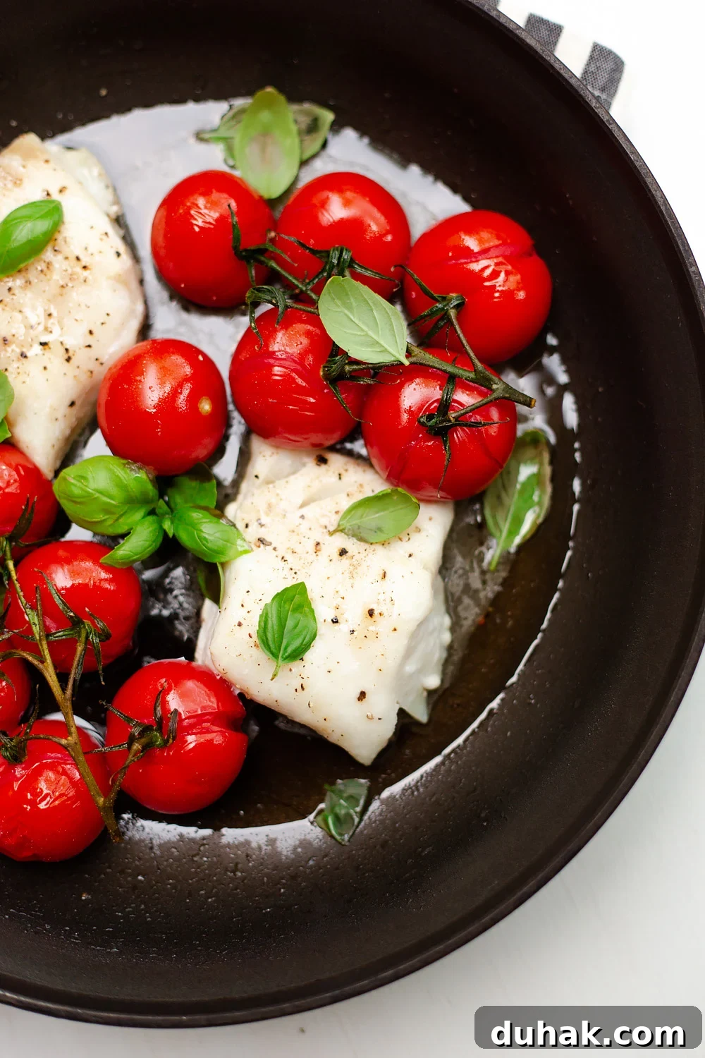 Tomato Basil Baked Cod with Lemon and Garlic 2 Cod with Tomatoes and Basil in a skillet.