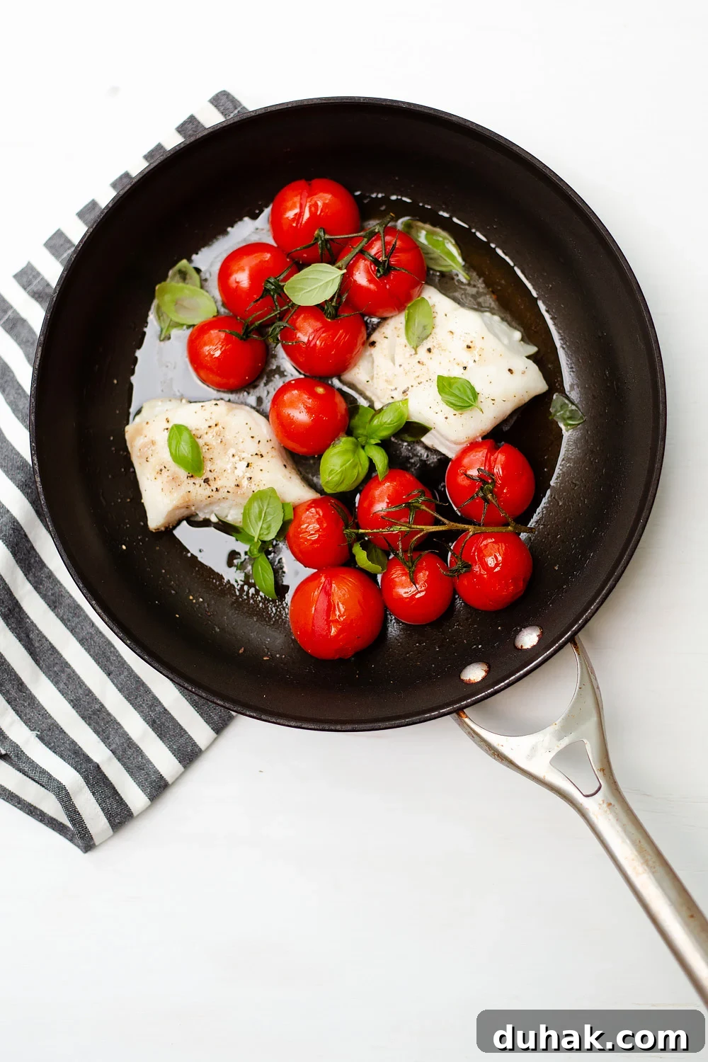 Tomato Basil Baked Cod with Lemon and Garlic 3 Cod with Tomatoes and Basil from above with a black and white napkin.