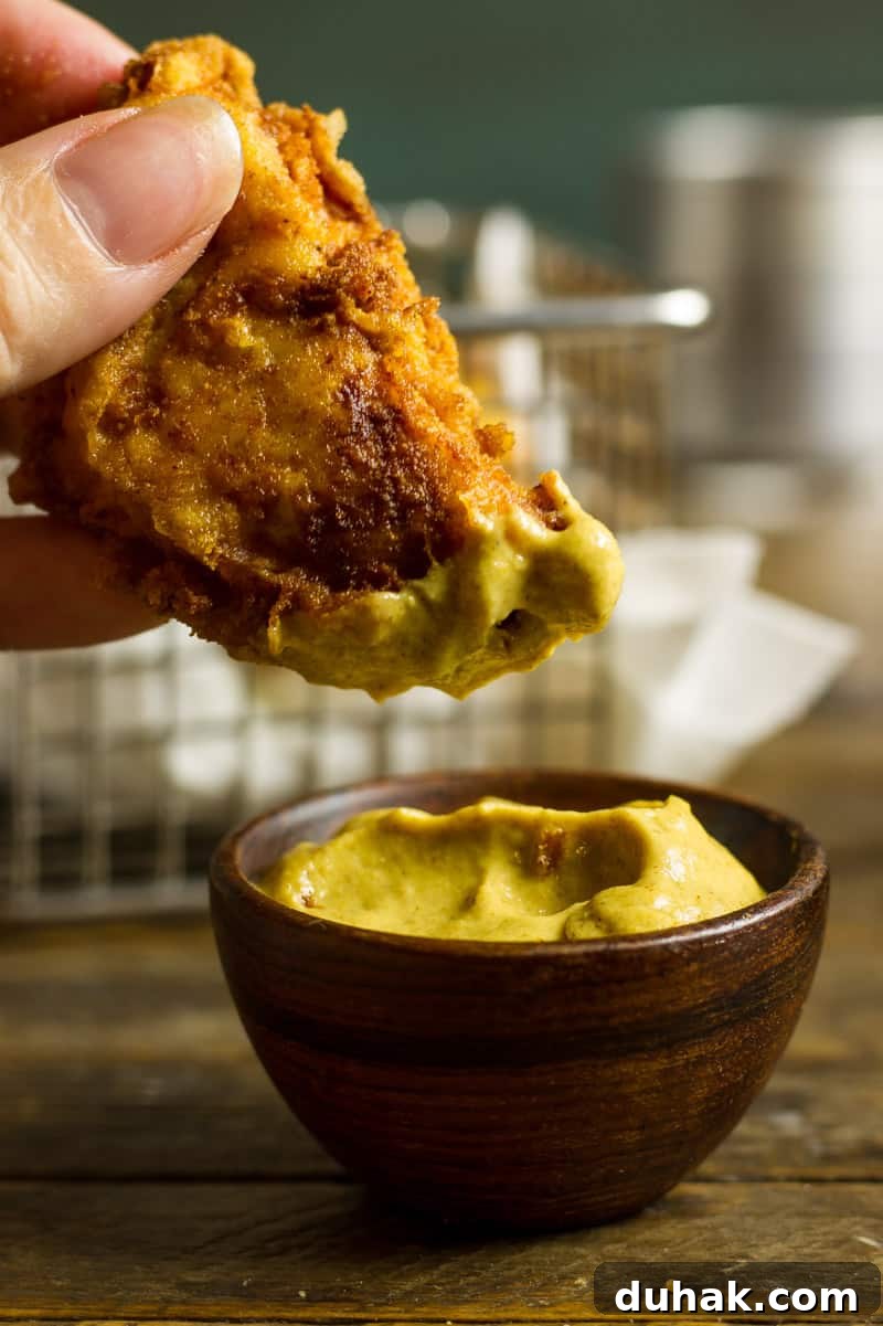 Pickle Brined Keto Fried Chicken in a basket with brown parchment paper and a pickle spear and some garlic mustard aioli.