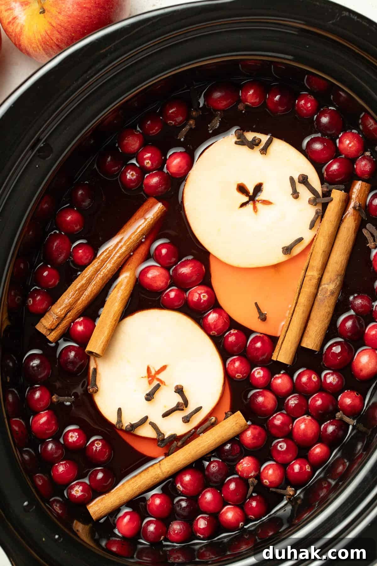 Alcohol-Free Wassail Recipe: Festive Mulled Apple Punch 4 Apples, cloves, cinnamon sticks, and cranberries in a slow cooker with wassail.