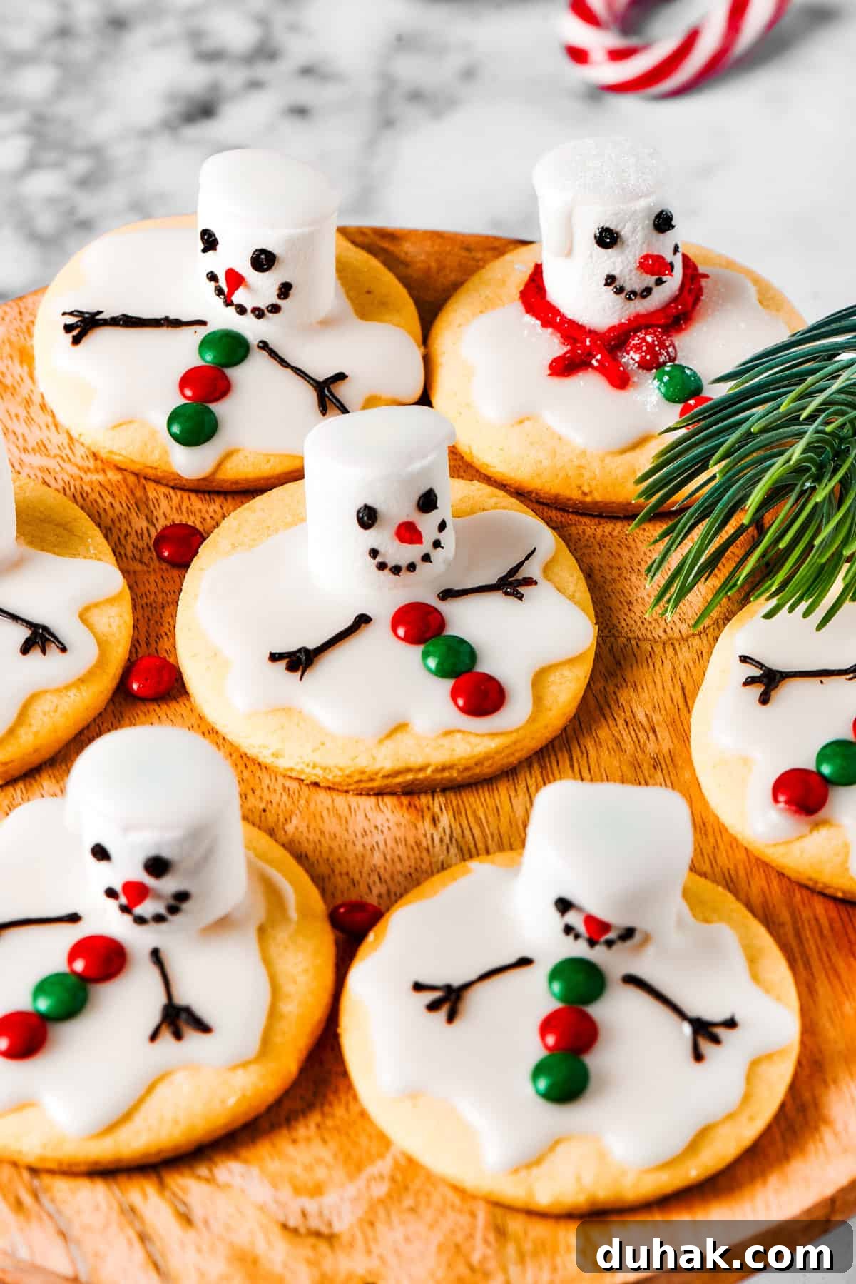 Melted snowman cookies on a wooden tray.