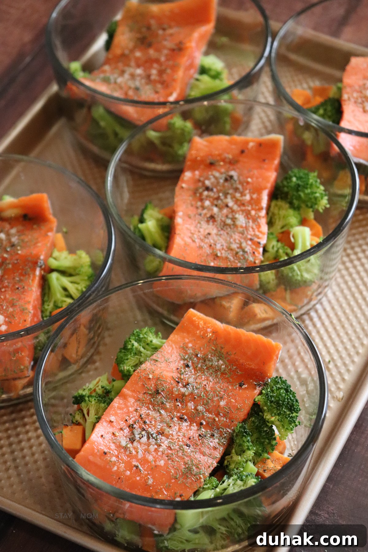 Maple-Glazed Salmon Bowls with Rice and Greens 4 Salmon meal prep bowls assembled with sweet potatoes, broccoli, and maple Dijon sauce before baking