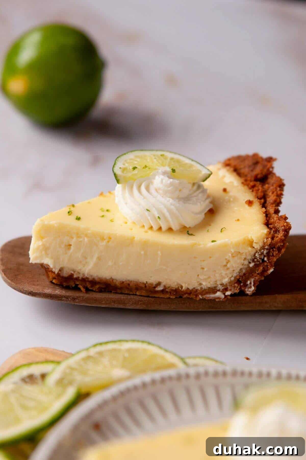 Key Lime Pie (Gluten-Free) — Zesty Citrus Dessert Recipe 2 A slice of gluten-free key lime pie with a buttery graham cracker crust, topped with whipped cream and a lime wedge.
