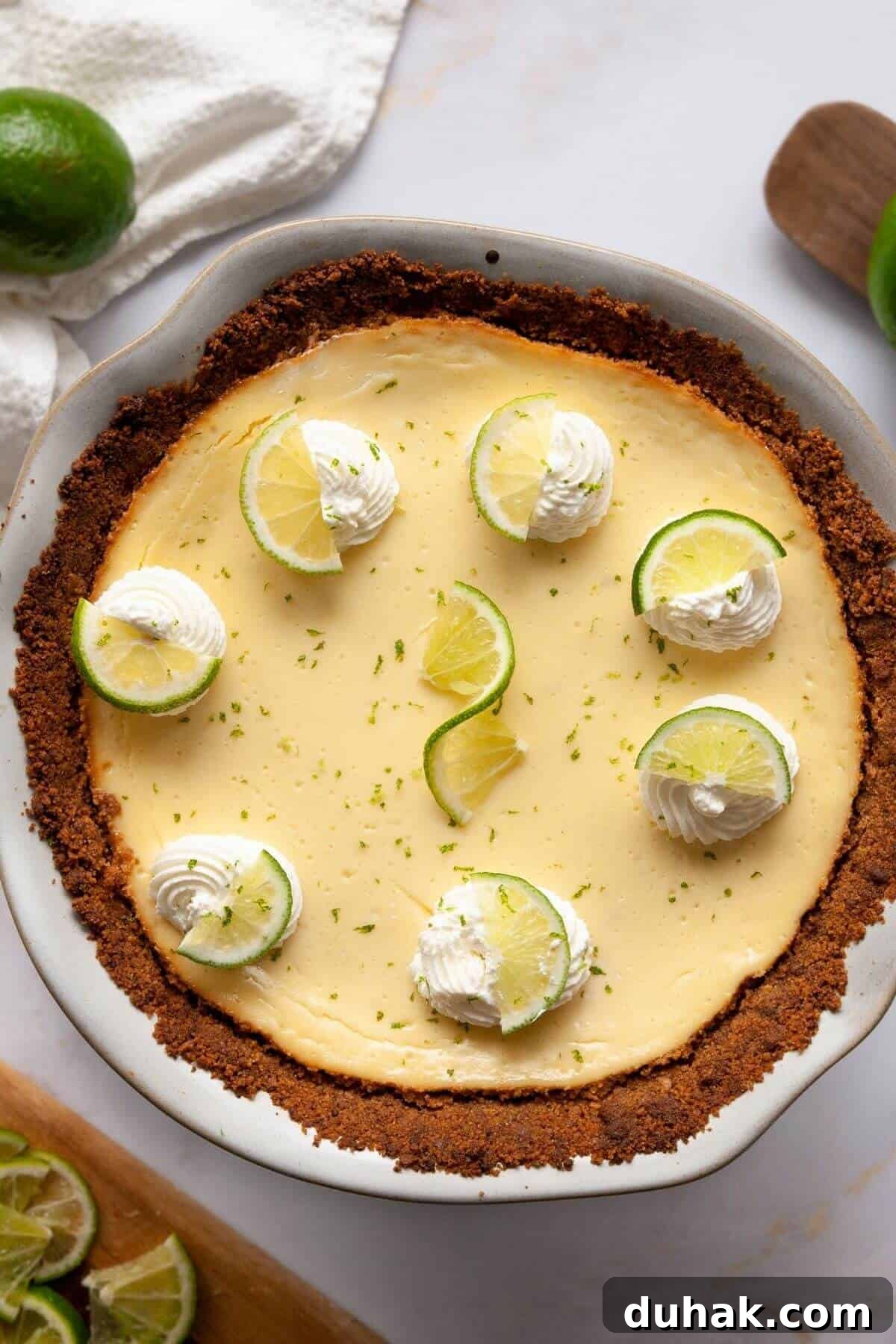 Key Lime Pie (Gluten-Free) — Zesty Citrus Dessert Recipe 12 Whole gluten-free key lime pie in a ceramic pie dish, topped with whipped cream swirls, lime slices, and fresh lime zest.