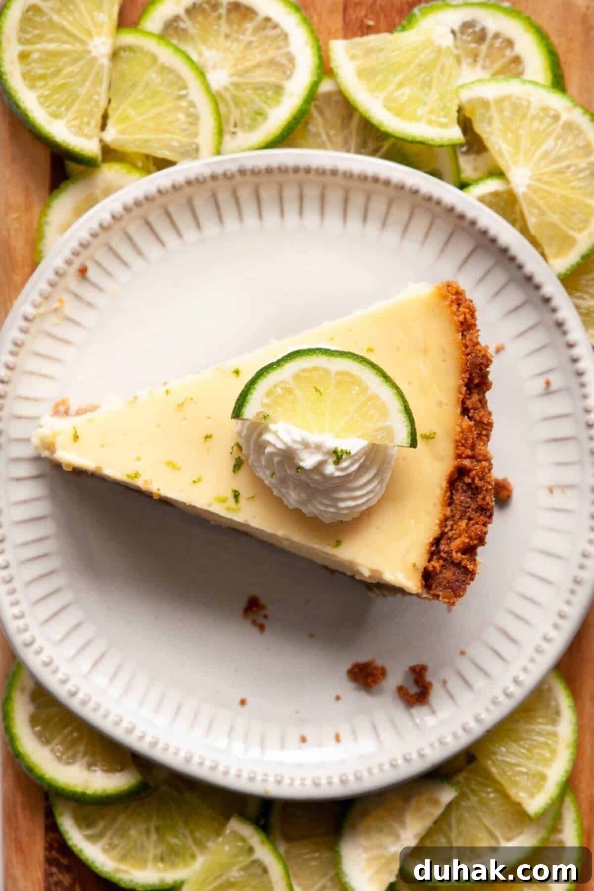 Key Lime Pie (Gluten-Free) — Zesty Citrus Dessert Recipe 13 A slice of creamy gluten-free key lime pie topped with whipped cream, a lime wheel, and zest.