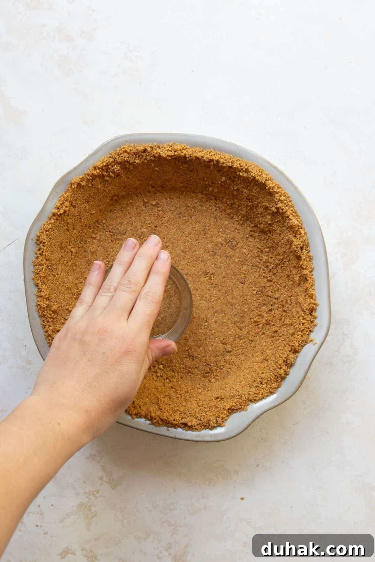 Key Lime Pie (Gluten-Free) — Zesty Citrus Dessert Recipe 5 Pressing gluten-free graham cracker crust into a pie dish with the bottom of a glass.