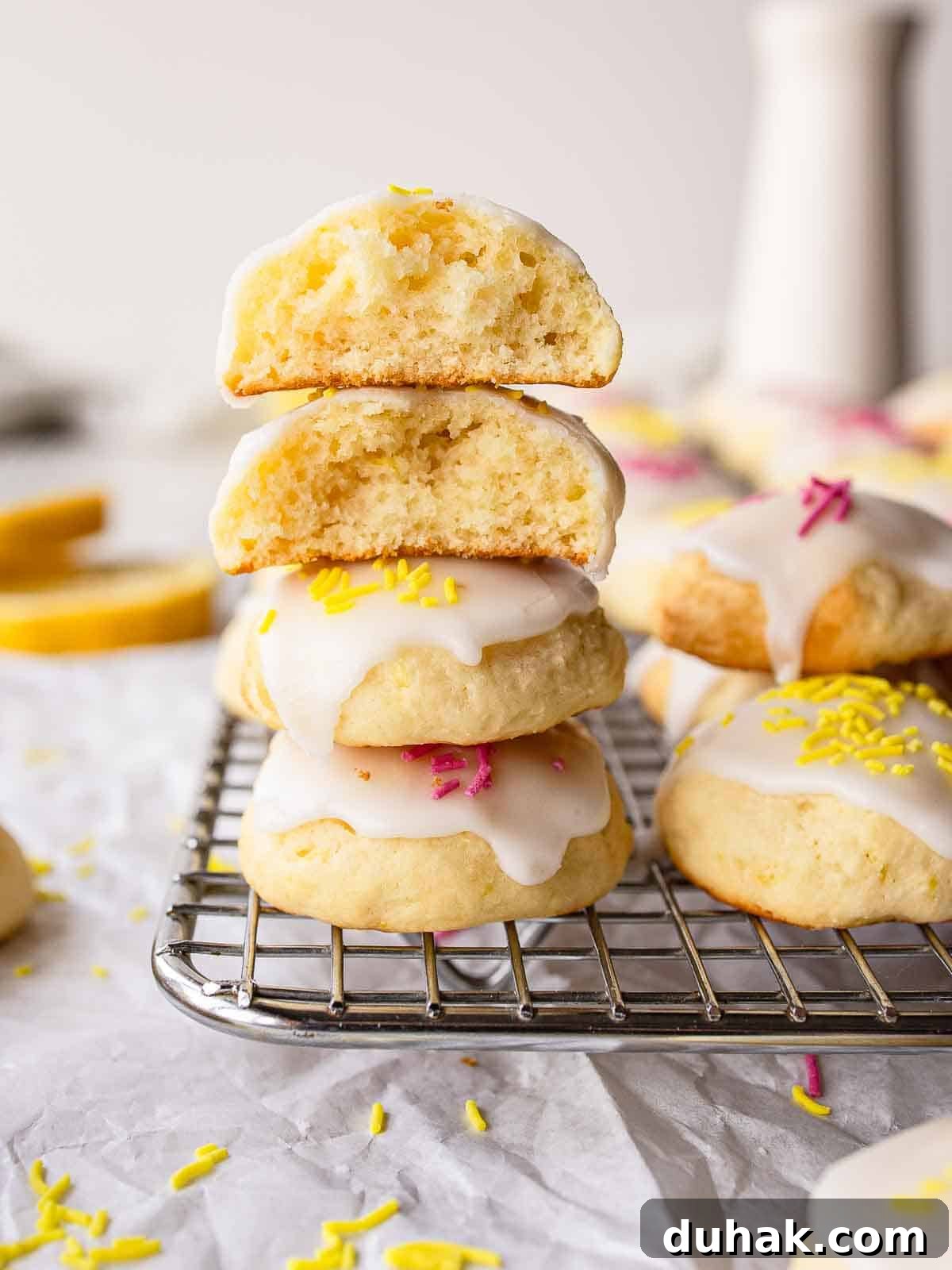 Lemon Ricotta Cookies Recipe — Soft, Zesty Citrus Cookies 2 Lemony Ricotta Cookies piled up like a tower with two at the top broken in half.