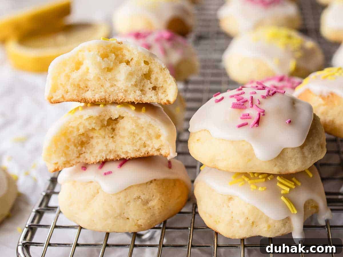 Lemon Ricotta Cookies Recipe — Soft, Zesty Citrus Cookies 13 Iced cookies piled one on top of the other with two cookie broken in half to reveal the inside.