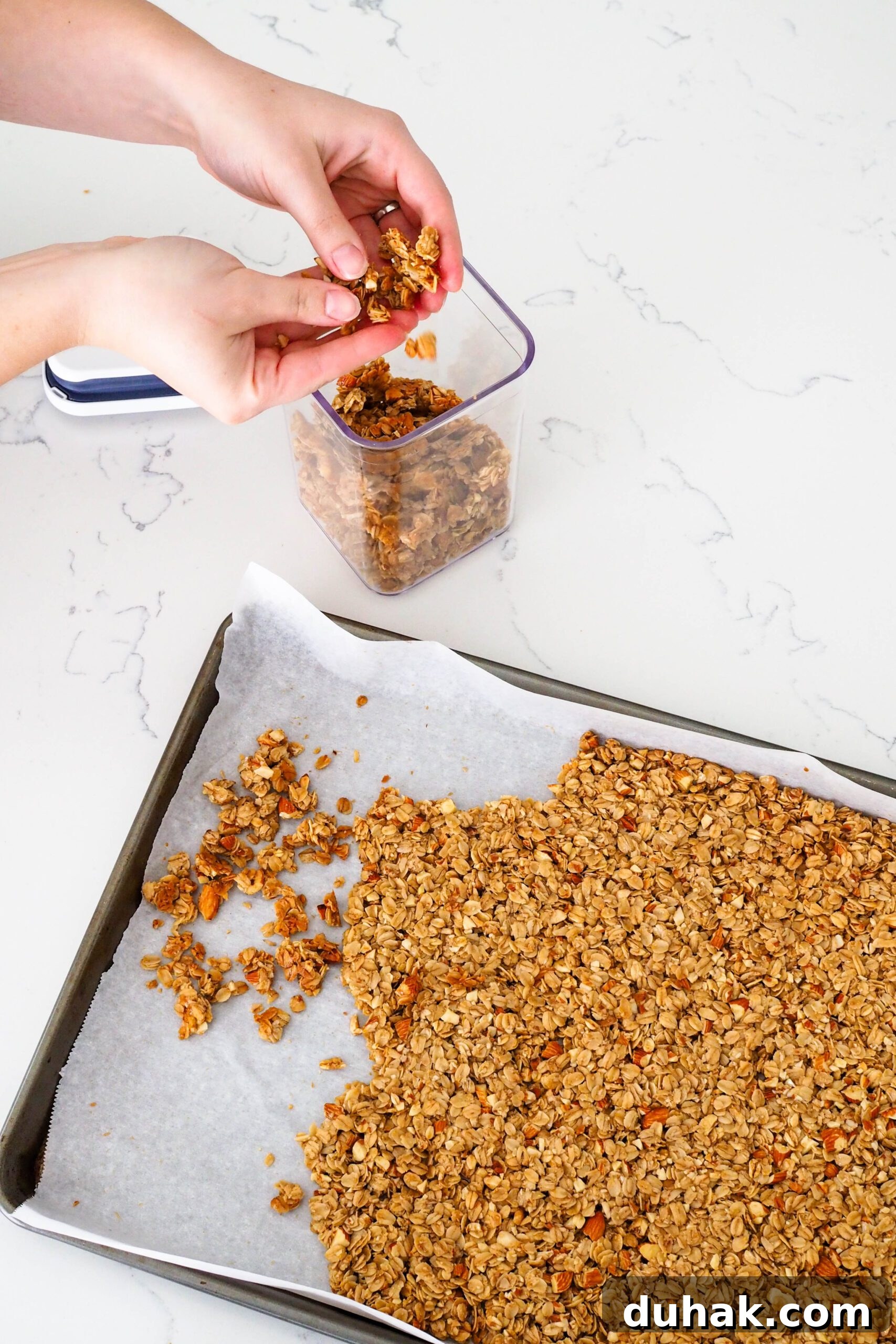 Two hands break up chunks of vanilla almond granola.