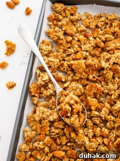 Vanilla almond granola in pan with a silver serving spoon.